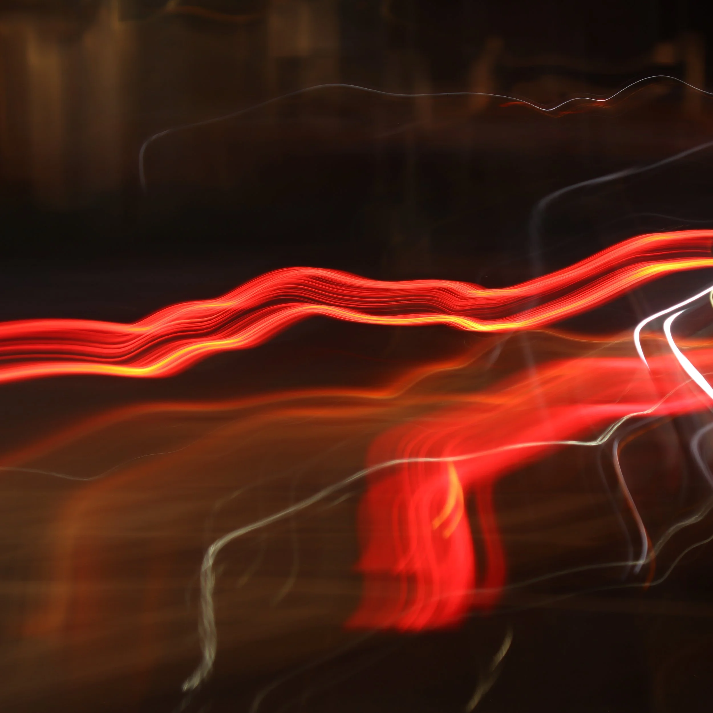 Blurry abstract image with red, white, and orange light streaks against a dark background.
