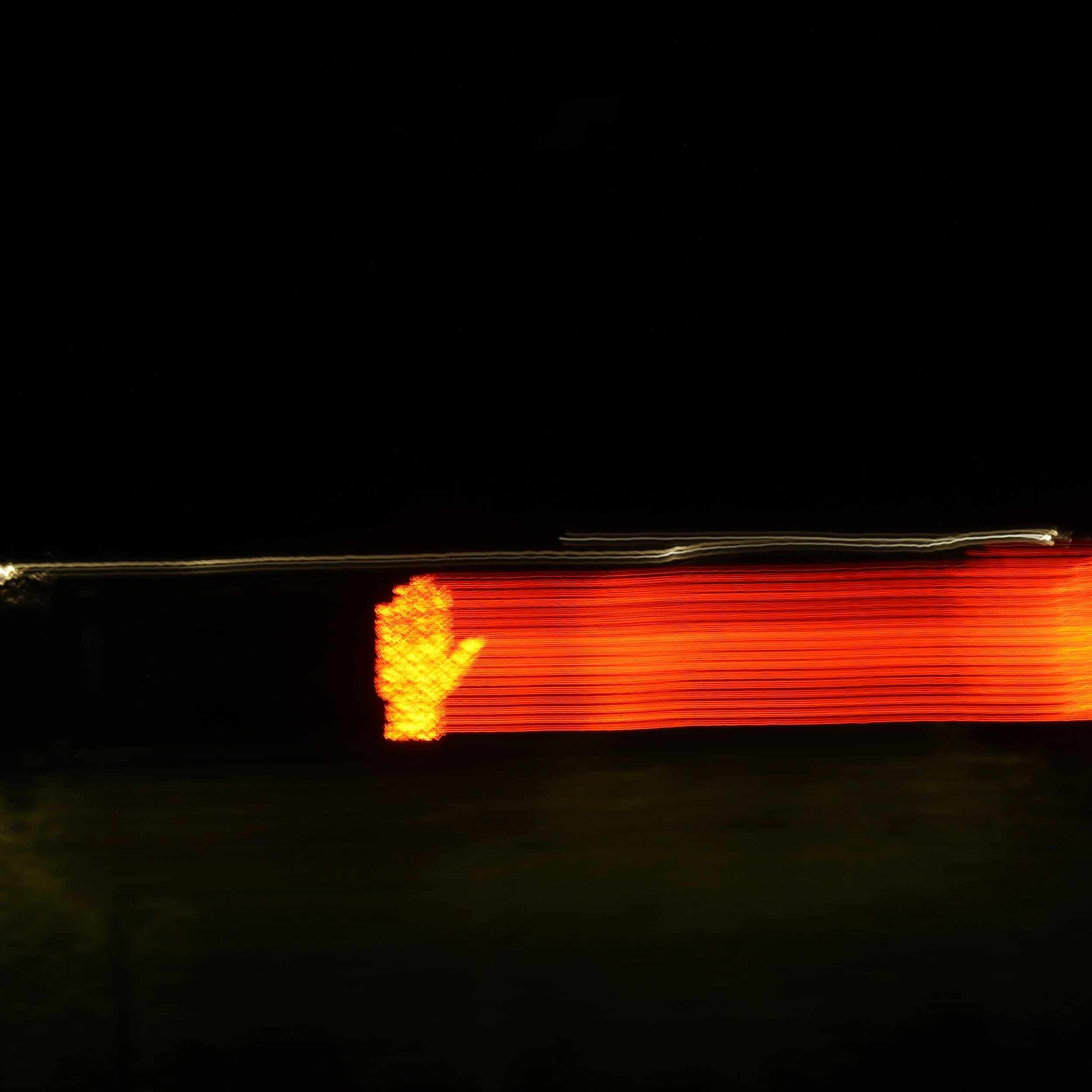 Nighttime scene of a highway with streaks of red and white lights from moving vehicles, and a dark sky in the background.