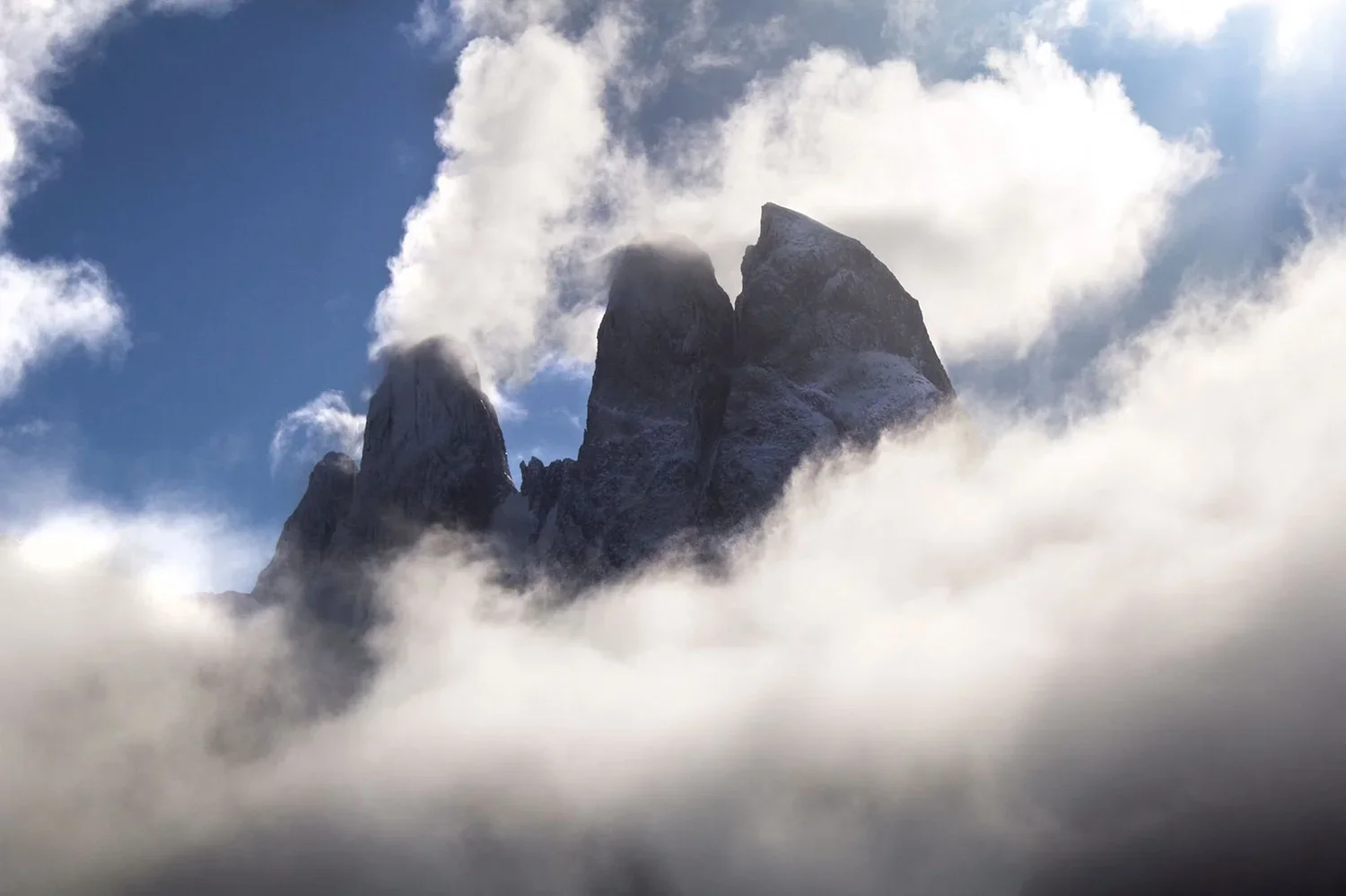 Snow-capped mountain peaks surrounded by clouds and mist