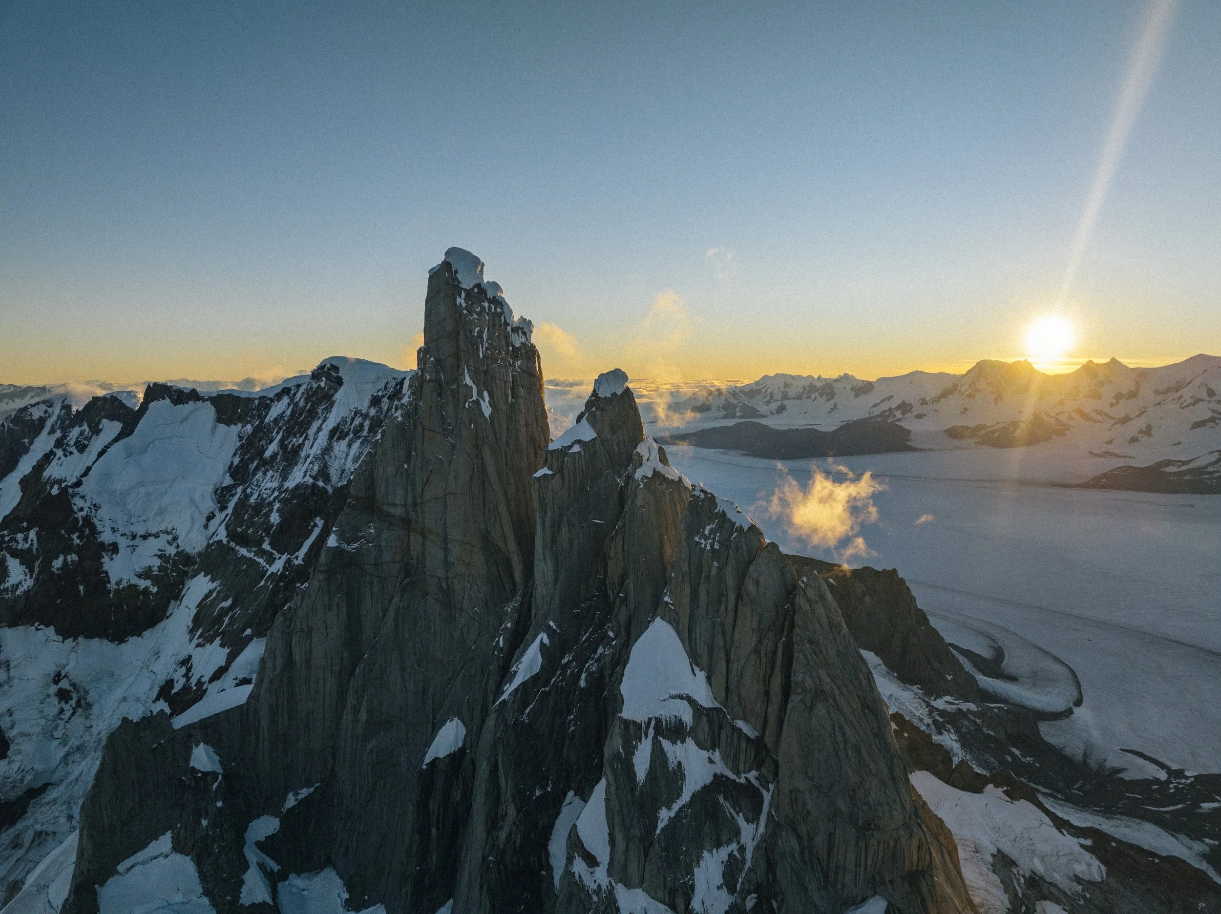 Snow-covered mountain peaks at sunrise with a clear sky.