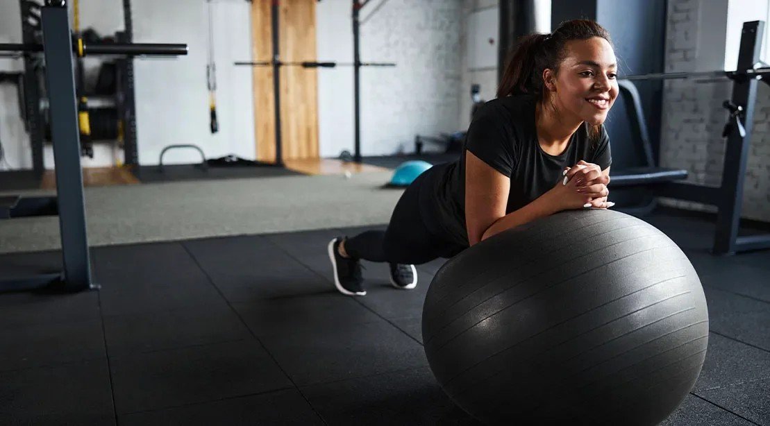 Woman doing a core exercise on a stability ball in a rehab gym
