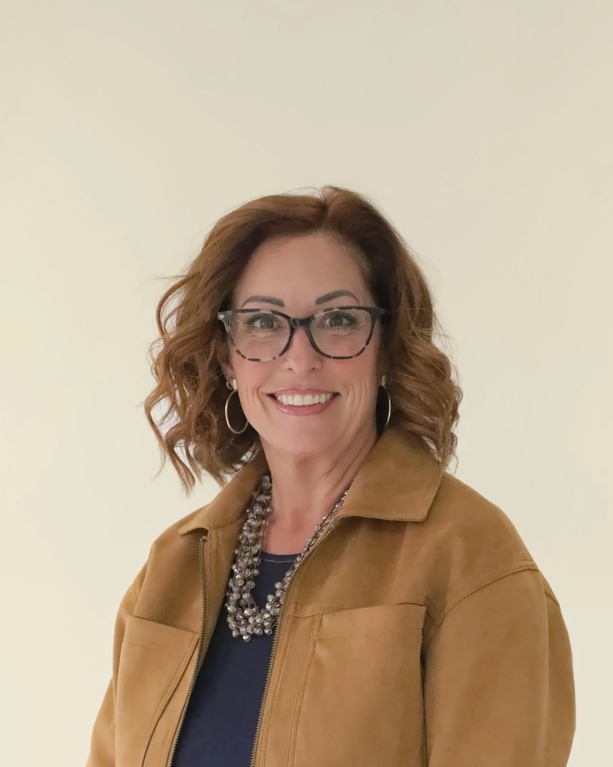 Wende Valentine smiling in a camel suede jacket