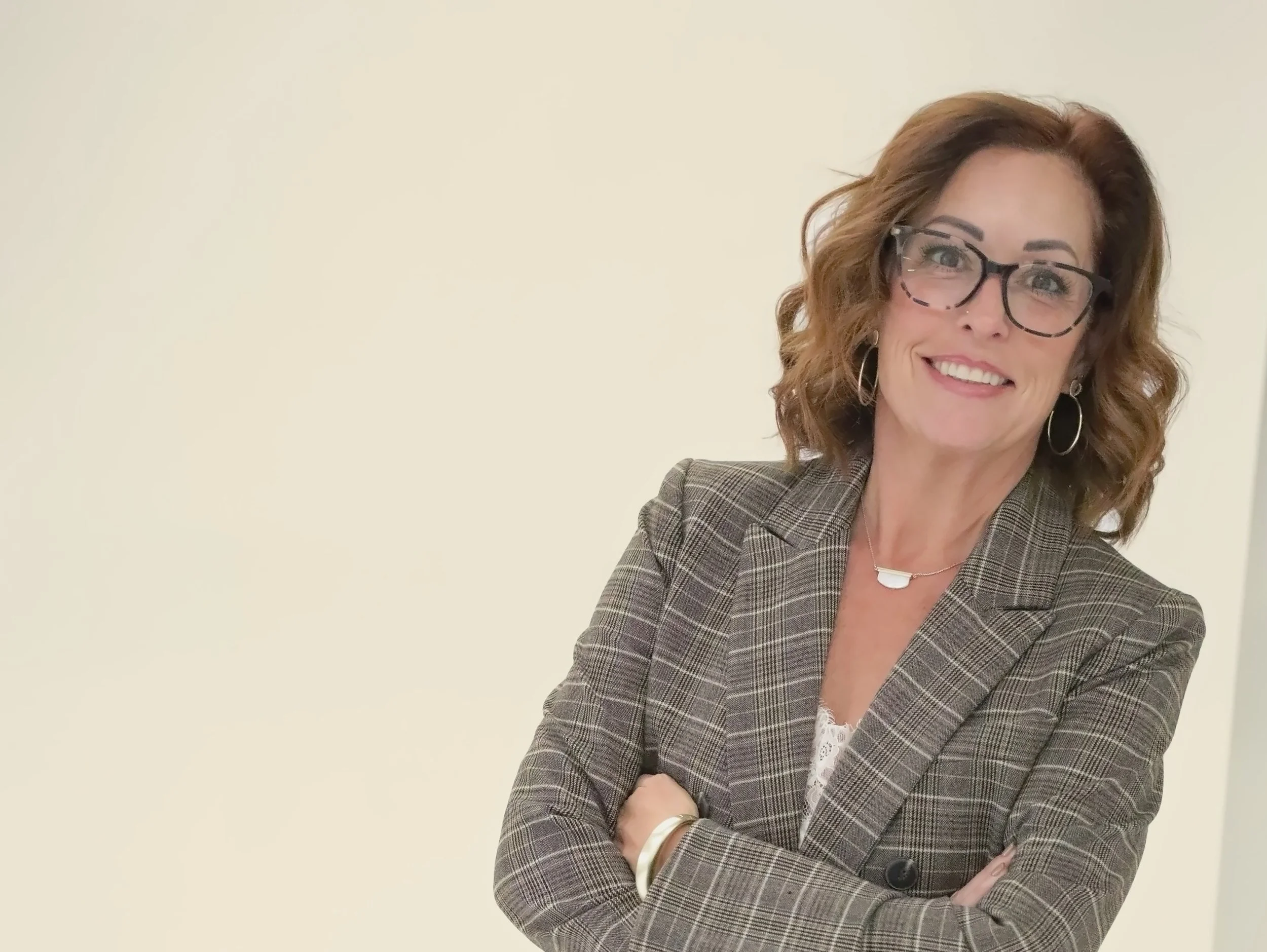 Wende Valentine in a plaid suit, arms crossed, smiling