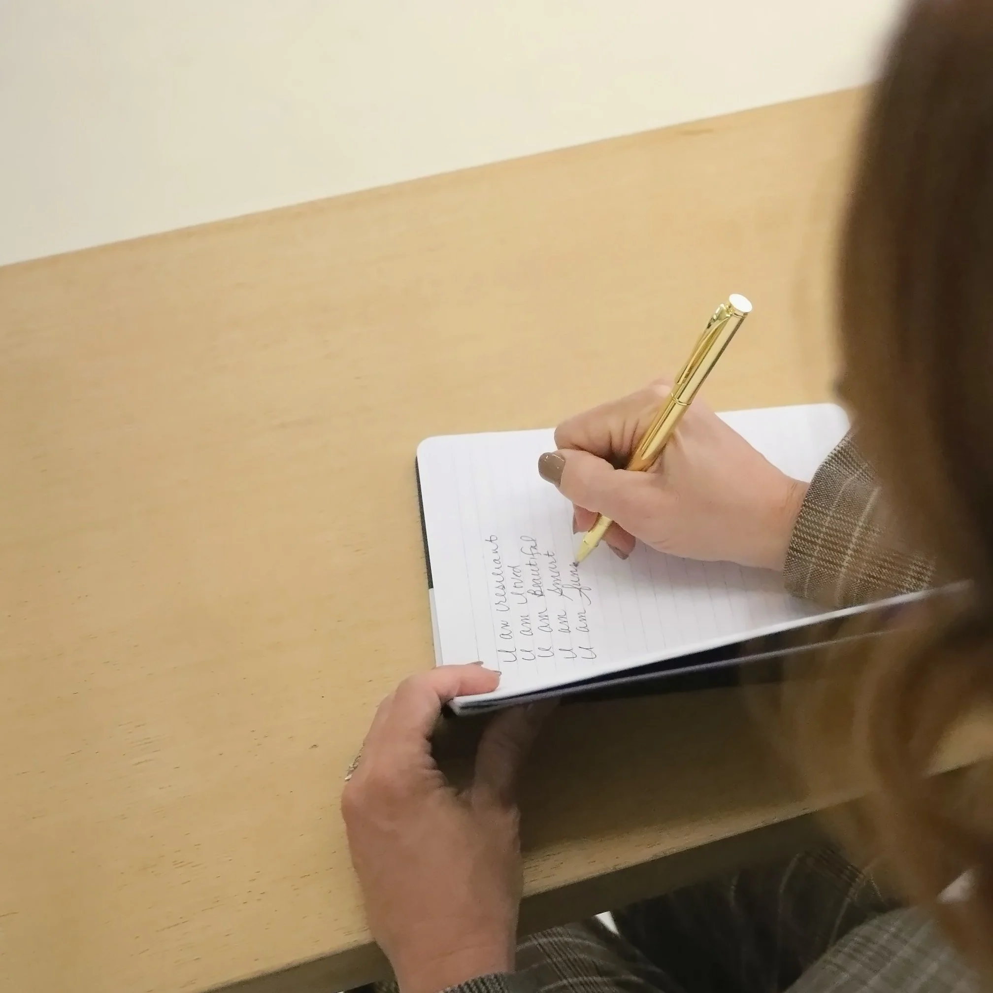 Wende Valentine writing in a journal with a gold pen