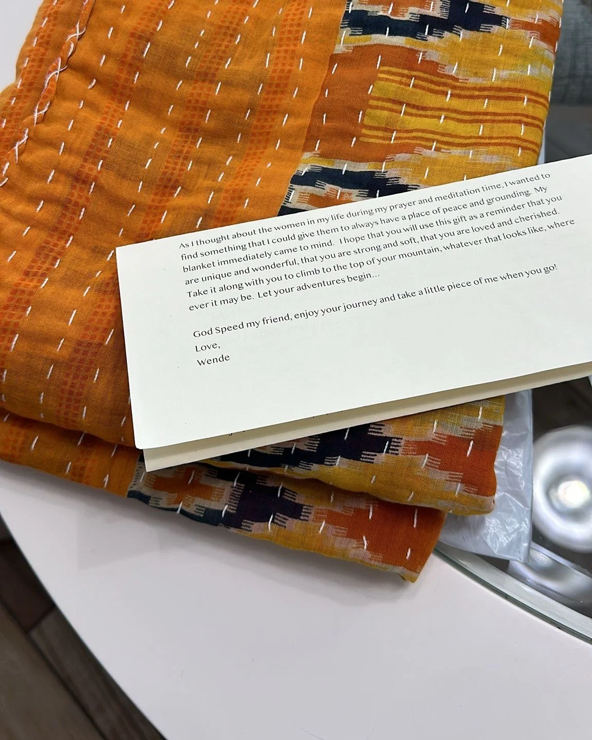 A folded orange kantha blanket with Wende's printed letter tucked on top