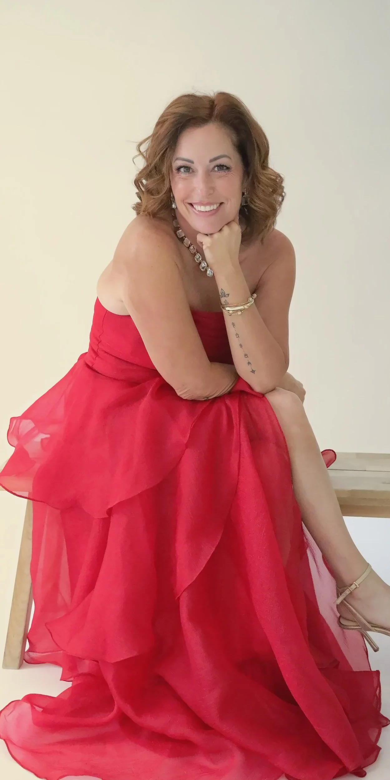 Wende Valentine in a red gown, seated on a bench