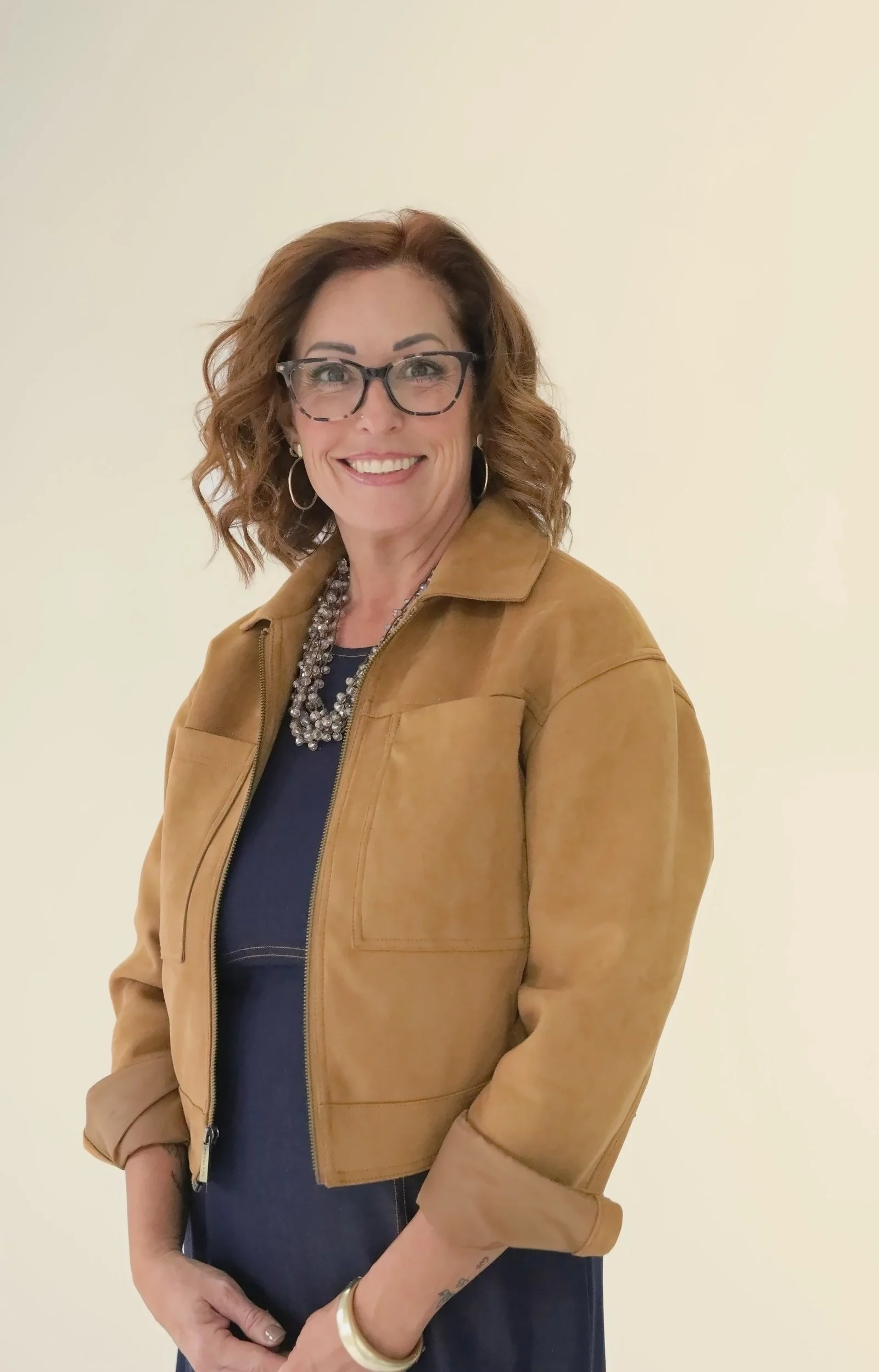 Wende Valentine smiling in a tan suede jacket and glasses