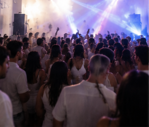 Crowd at a concert or music event with stage lights and smoke effects.