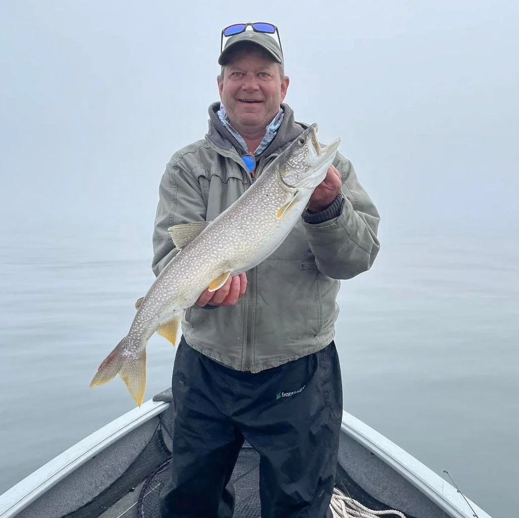 Brian Iverson on a boat holding a lake trout