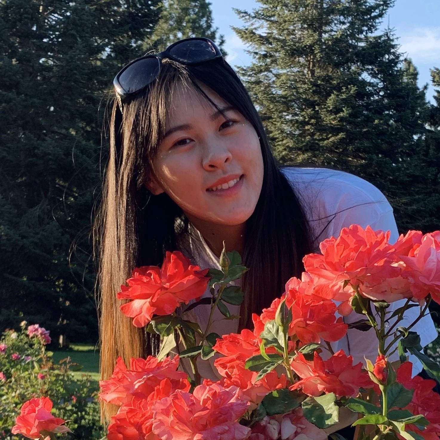 Picture of Emily, standing behind vibrant flowers.