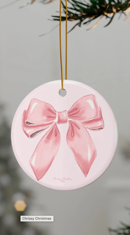 Christmas ornament ornament with pink bow design hanging on a Christmas tree branch