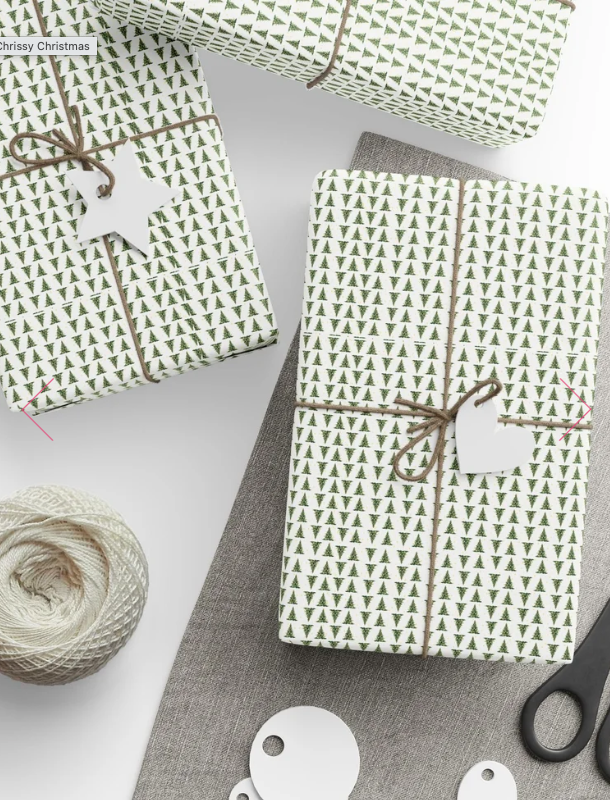 Christmas presents wrapped in green and white paper with small Christmas trees, tied with brown string, with a white star-shaped tag, on a white and gray surface with scissors and twine.