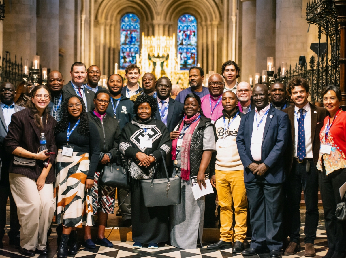A group of diverse people gathered inside a church with stained glass windows and a golden altar in the background.