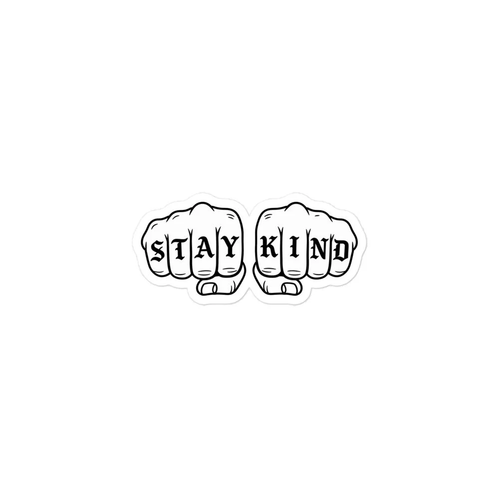 White STAY KIND sticker with black tattoo-style fists and lettering across the knuckles