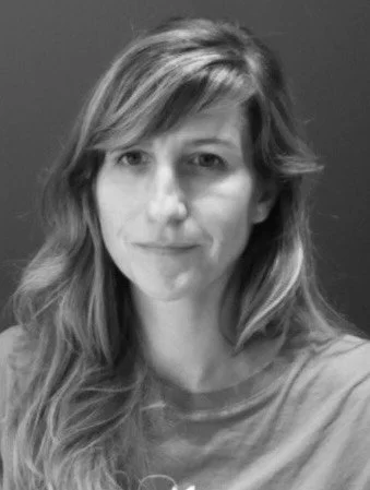 Portrait en noir et blanc d'une femme avec des cheveux longs et ondulés, portant un t-shirt, regardant vers l'objectif.