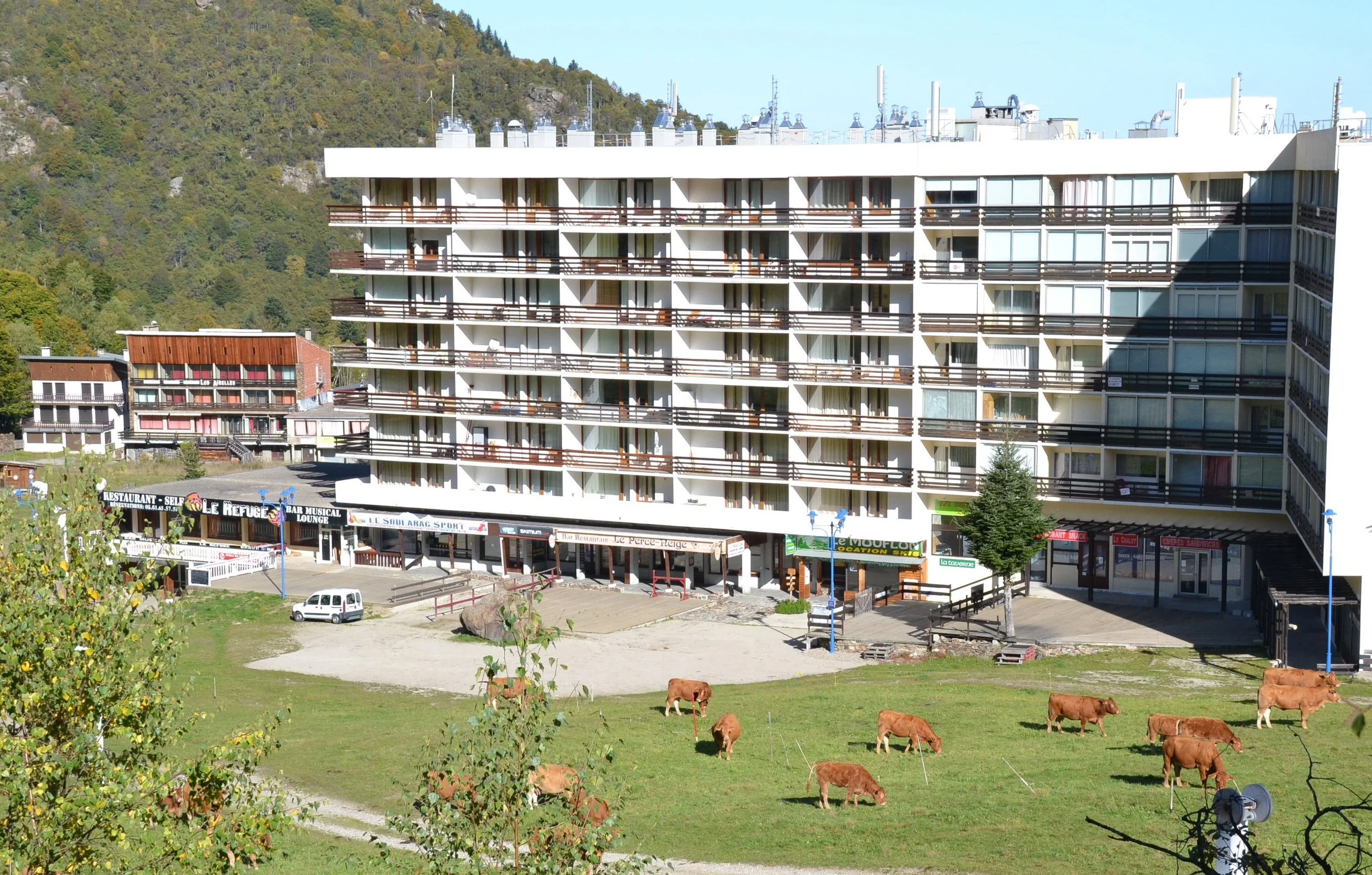 Un bâtiment de l'époque moderne d'appartements en forme situé dans des montagnes verdoyantes.