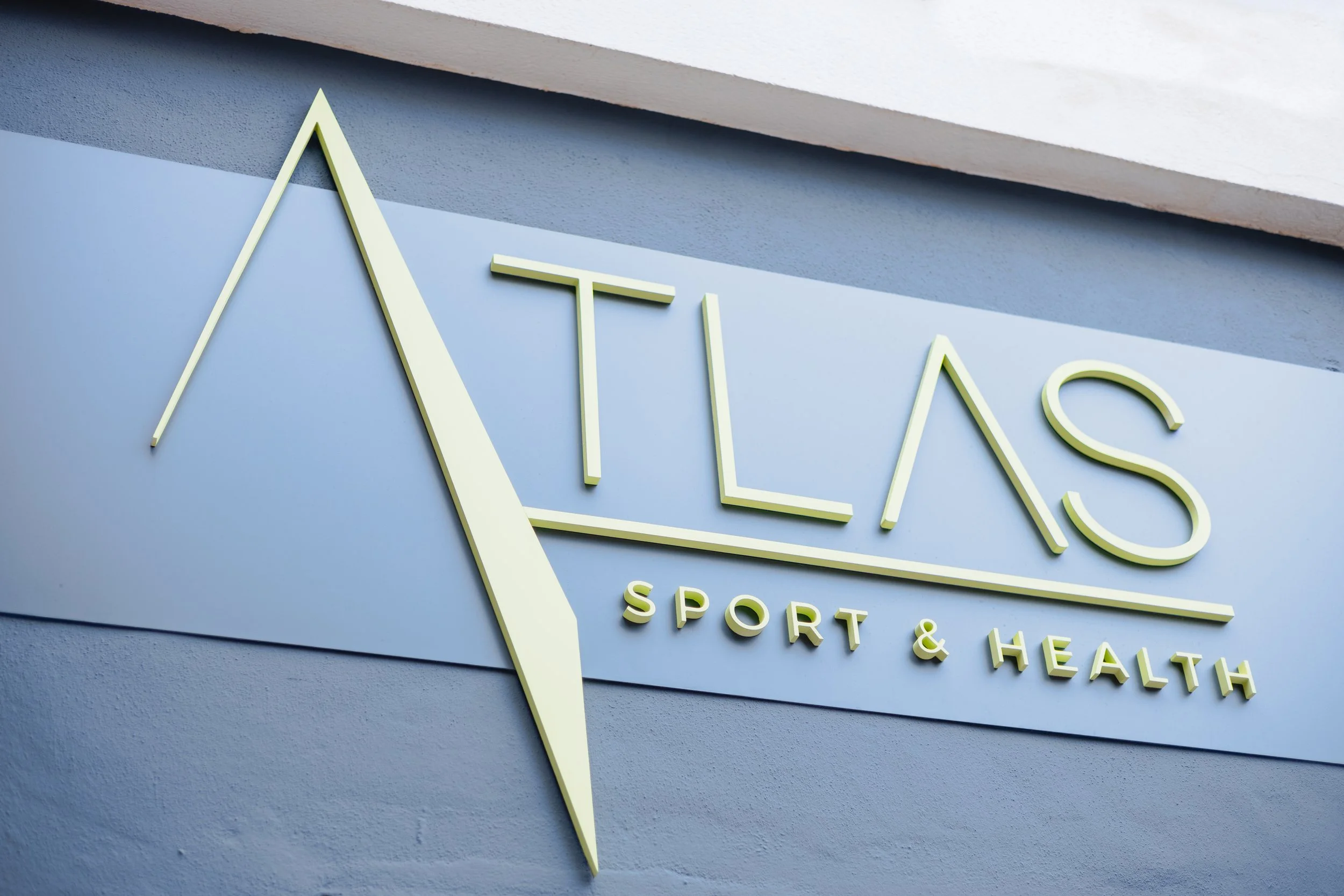 Logotipo y señalética de fachada para Atlas Sport & Health — identidad de marca.