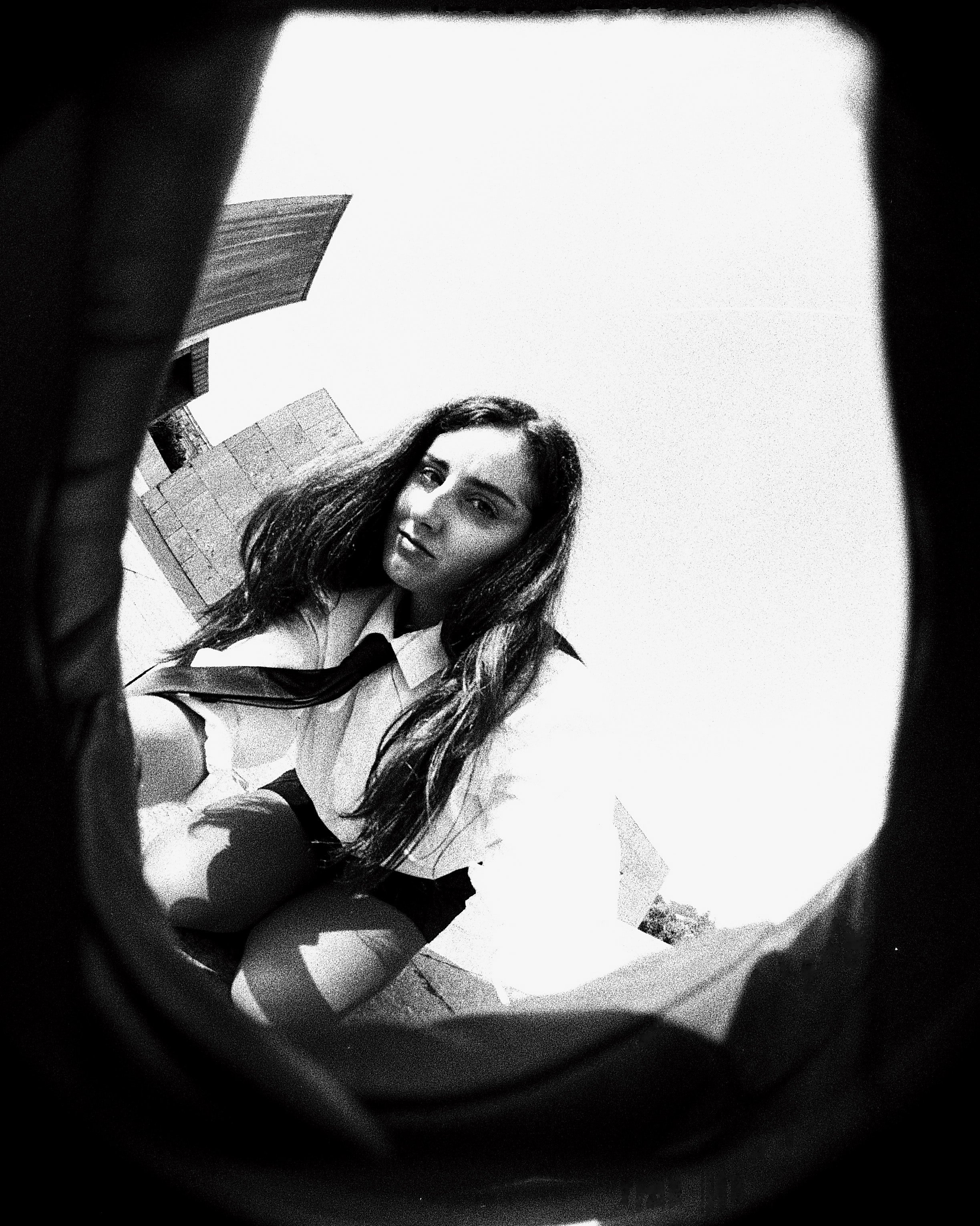A black and white photo of a woman with long wavy hair, wearing a uniform or costume, and looking at the camera.