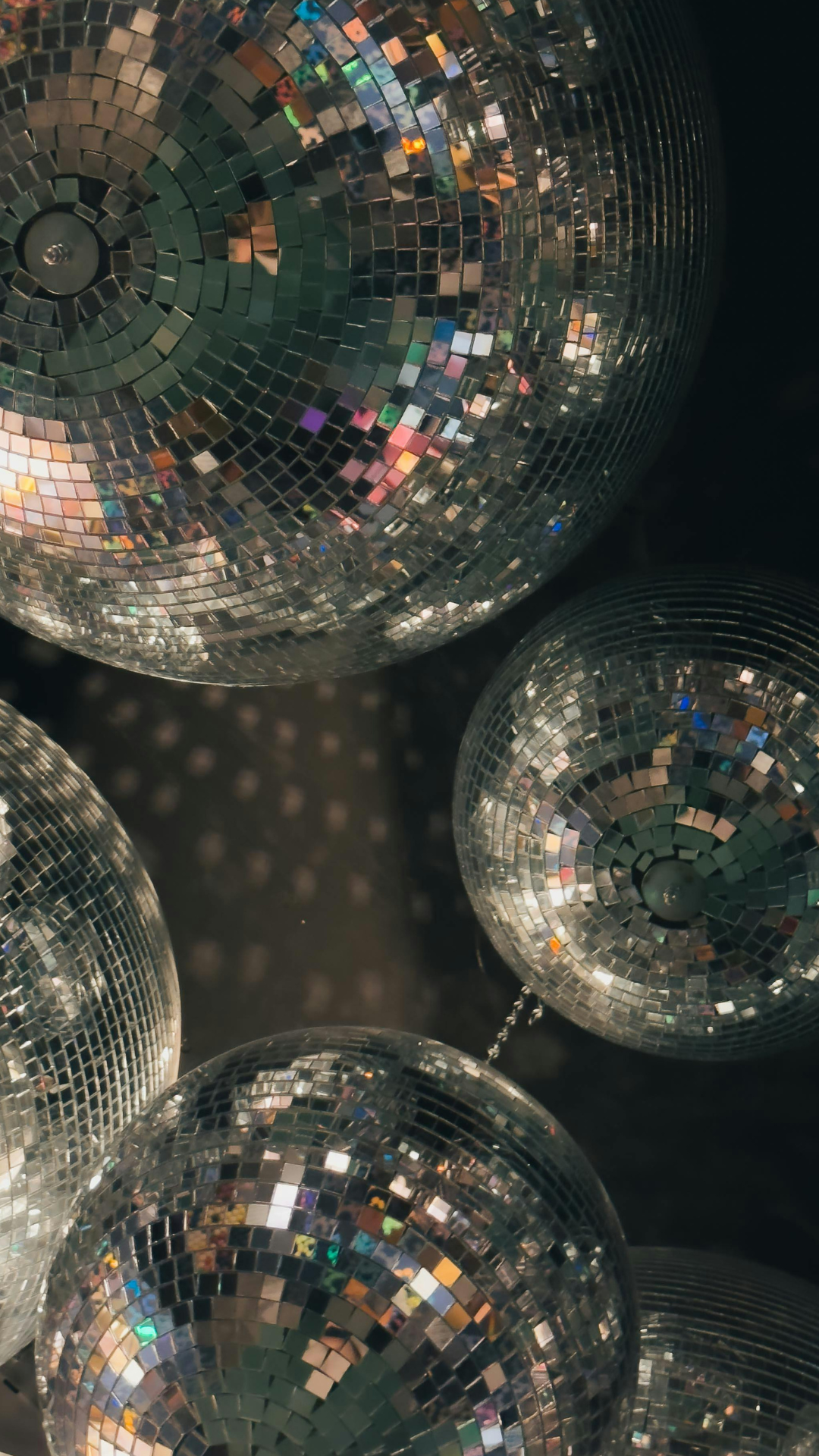 Close-up of disco balls reflecting multicolored light.