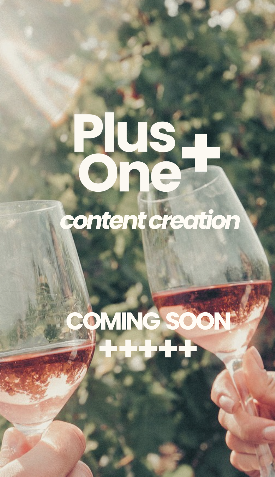 Two hands holding glasses of rosé wine outdoors, with a blurred background of plants and sunlight.