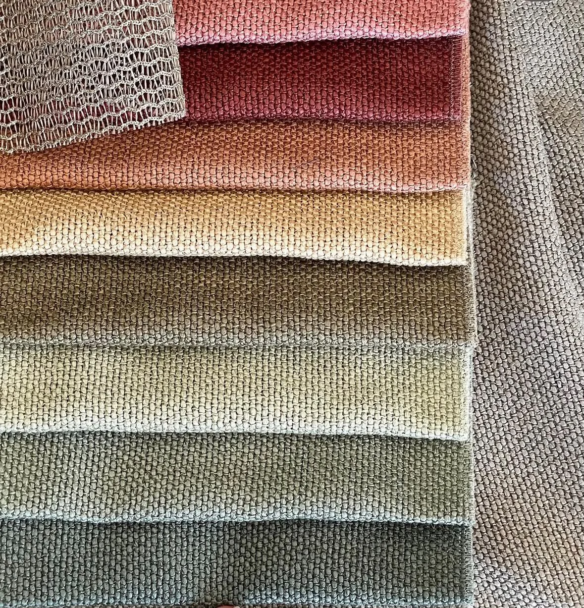 Multiple fabric swatches in various colors and textures stacked and arranged on a surface.