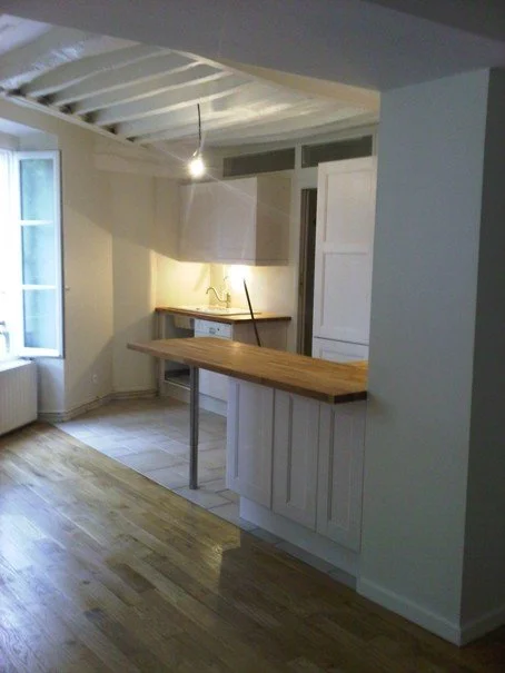 Cuisine en cours de rénovation, avec un plafond blanc, un plan de travail en bois, et un éclairage suspendu.
