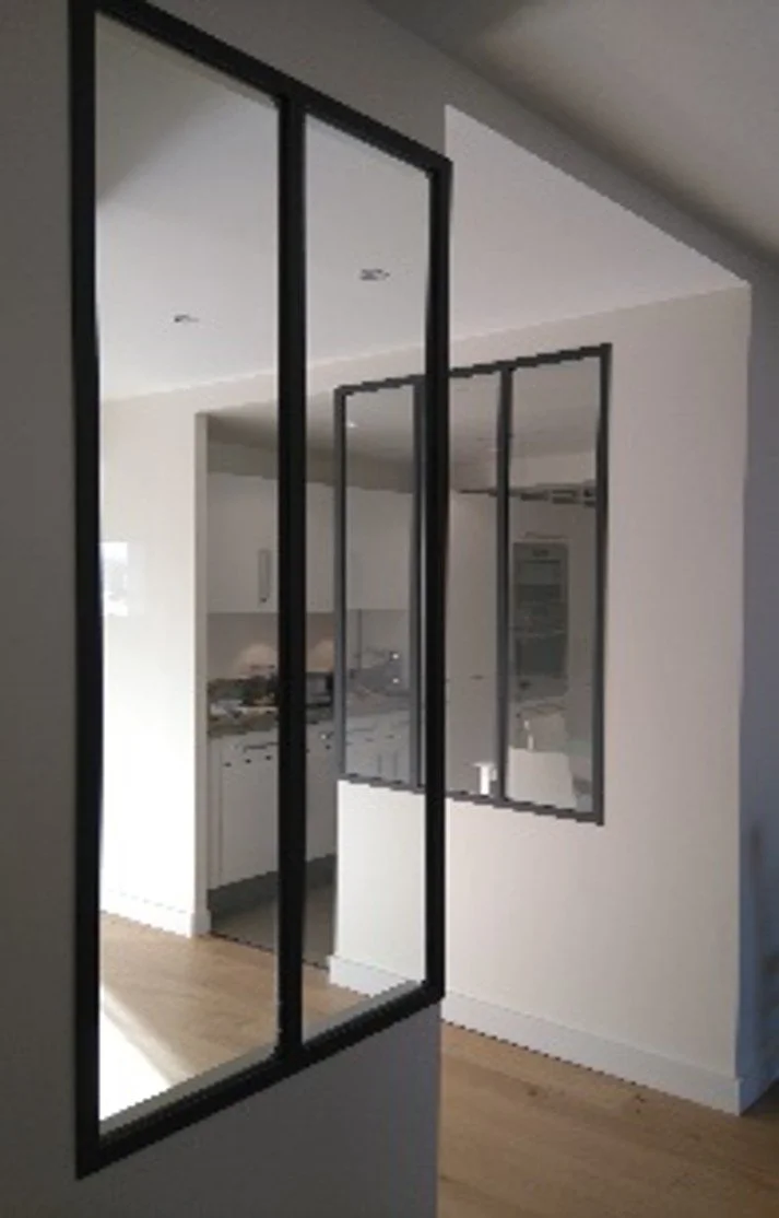 Miroir rectangulaire accroché à un mur, reflétant partiellement une cuisine moderne avec des armoires blanches et un plan de travail.