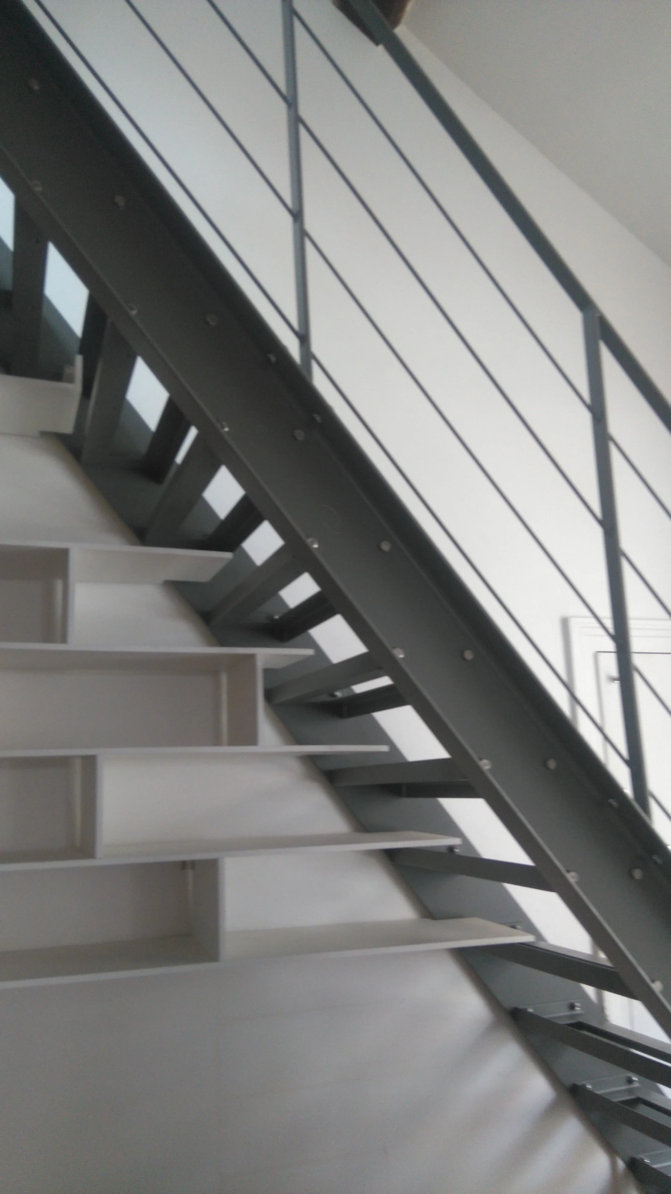 Escalier intérieur en métal avec mains courantes en acier, vue de dessous vers le haut.
