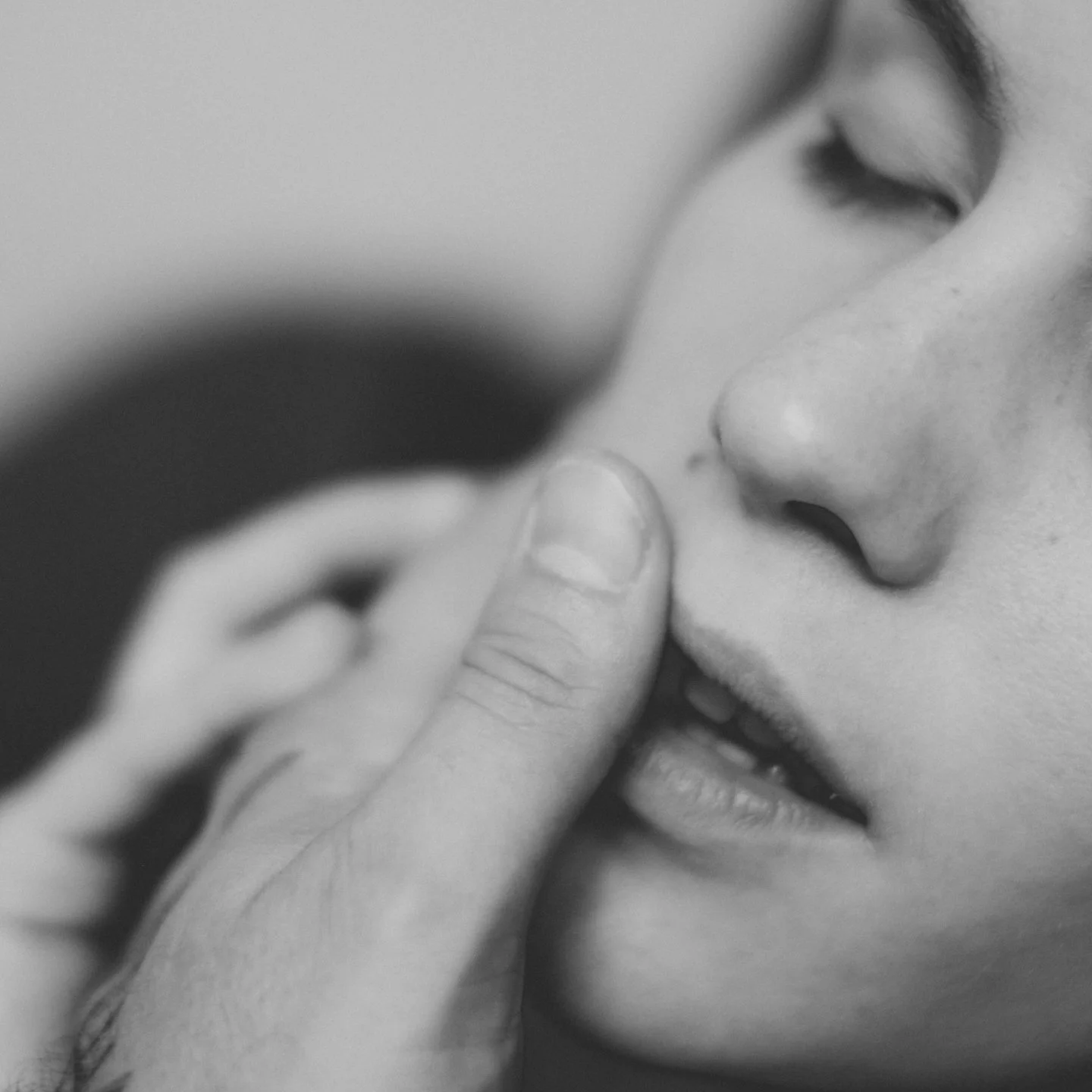 Black-and-white close-up of a sleeping baby resting against an adult’s face.