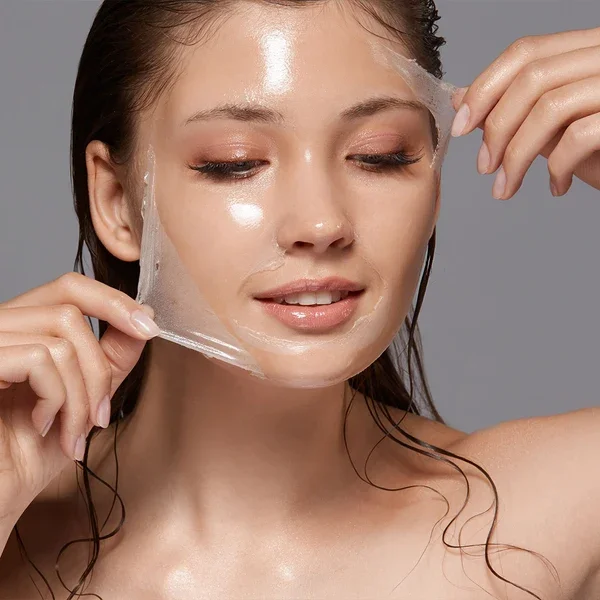 A woman peeling off a facial sheet mask.
