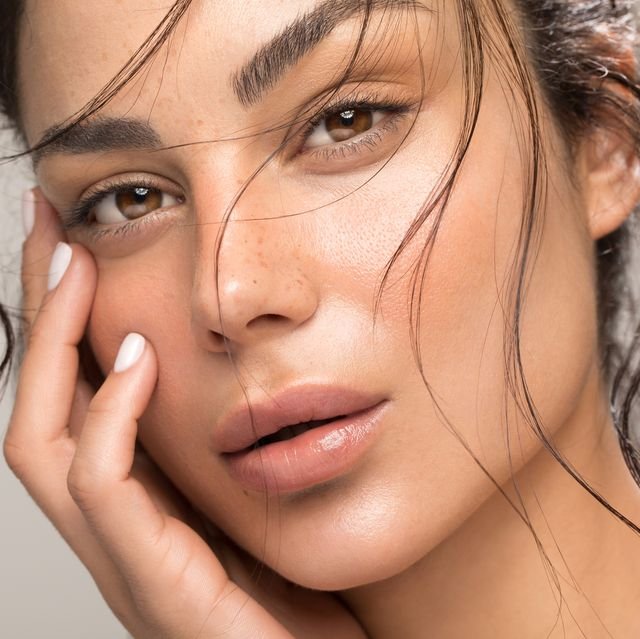 Close-up of a woman's face with brown eyes, full lips, and long brown hair softly framing her face.