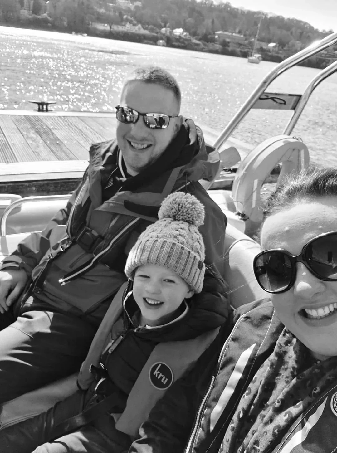 Black and white family photograph of Mike, Jenny and Oliver from Oliver Francis Interiors enjoying a boat trip together.