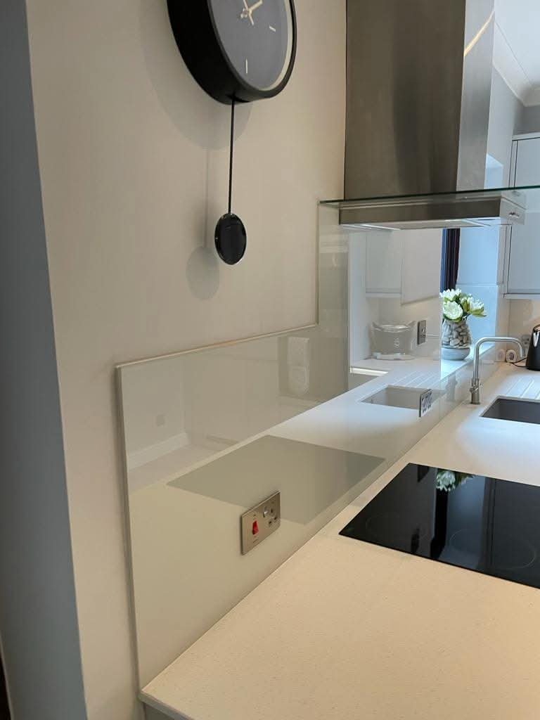 Modern kitchen worktop with integrated sink, induction hob, stainless steel extractor hood and sleek glass splashback.