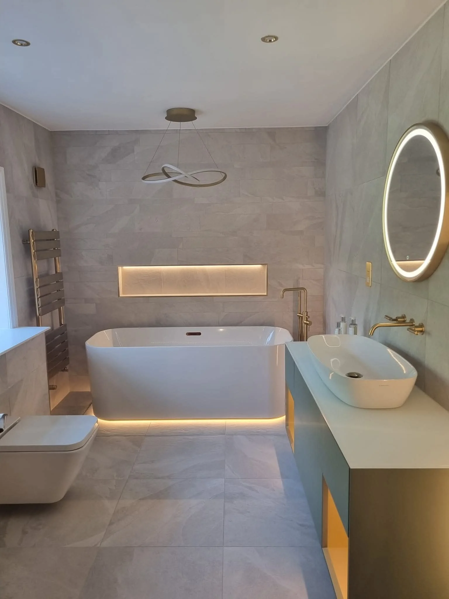 Completed bathroom renovation in Oldham by Oliver Francis Interiors, featuring a freestanding bath, illuminated niche and modern vanity unit.