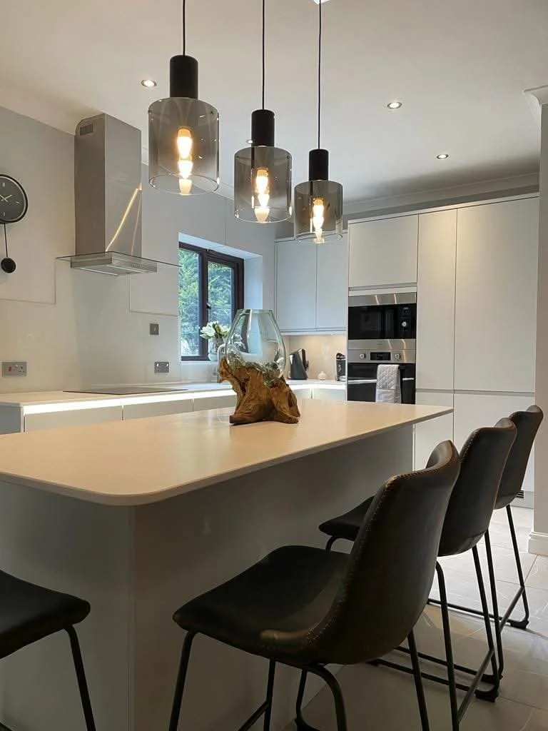 Contemporary kitchen island with breakfast bar seating, three statement pendant lights and sleek handleless cabinetry.