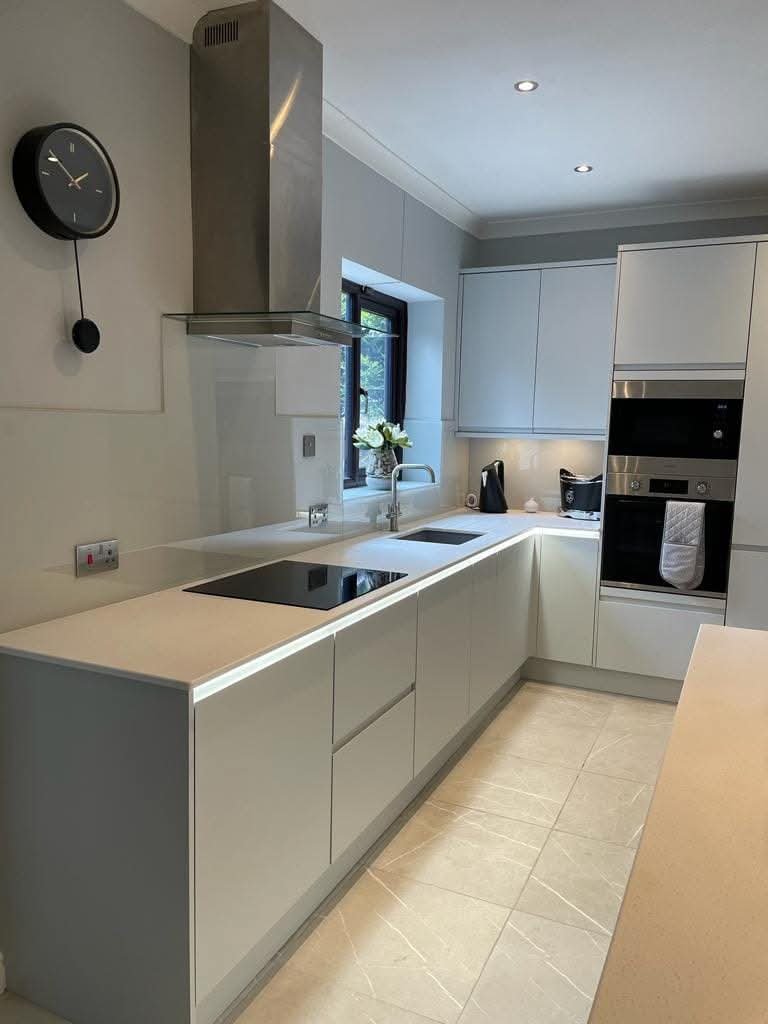 Fully renovated contemporary kitchen featuring light-grey handleless cabinets, integrated appliances, sleek worktops and modern lighting.