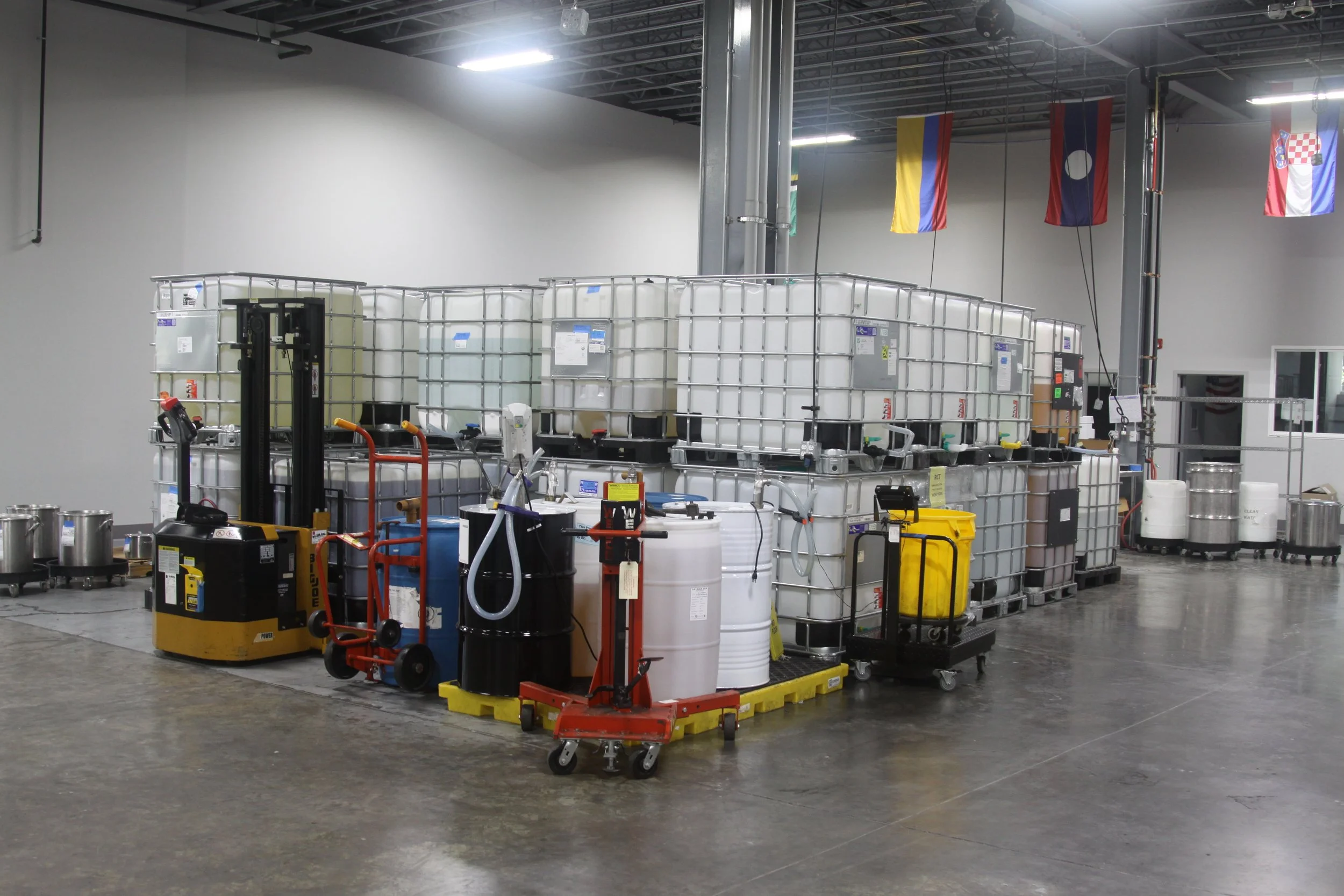 Warehouse or industrial facility with large water containers, equipment, and flags hanging from ceiling.