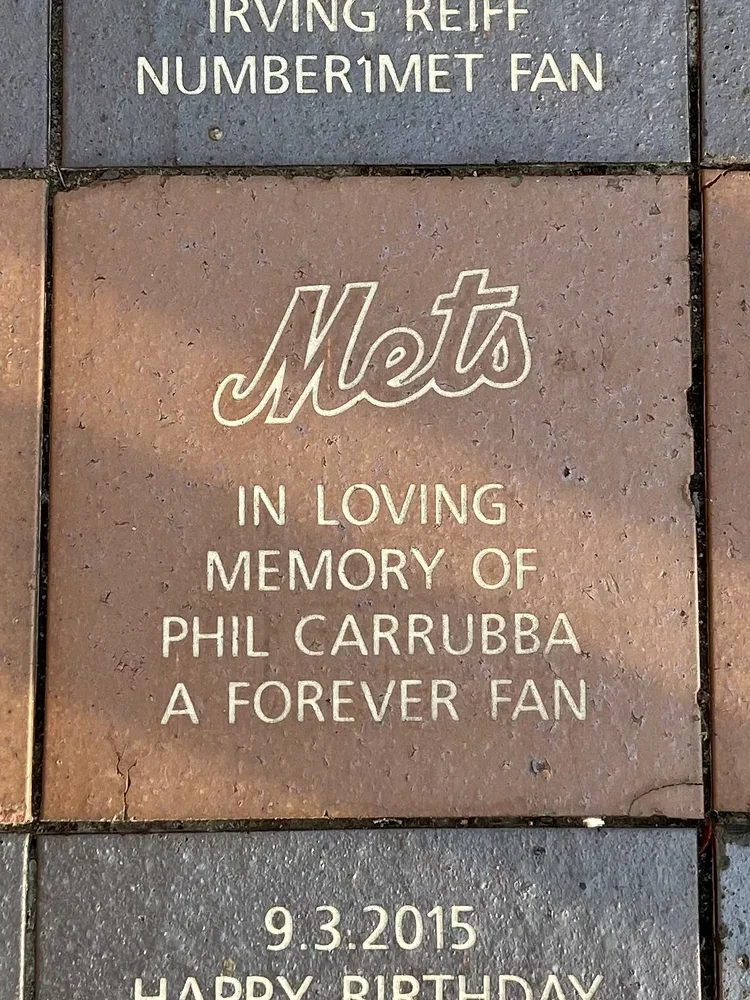 Brick sidewalk with engraved tribute plaque for Mets fan Phil Carrubba, dated September 3, 2015.