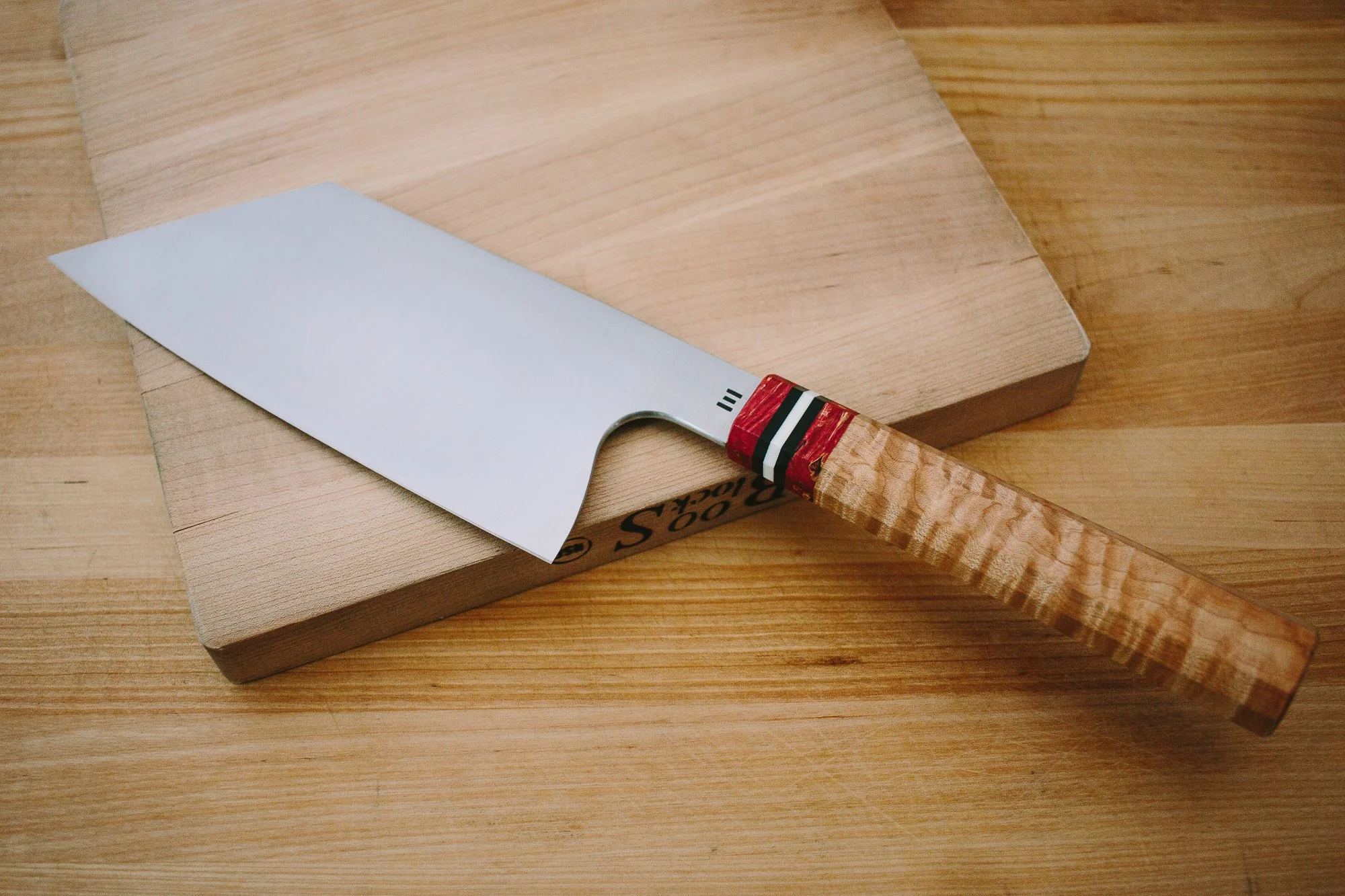 White-bladed chef’s knife with a wooden handle resting on a wooden cutting board