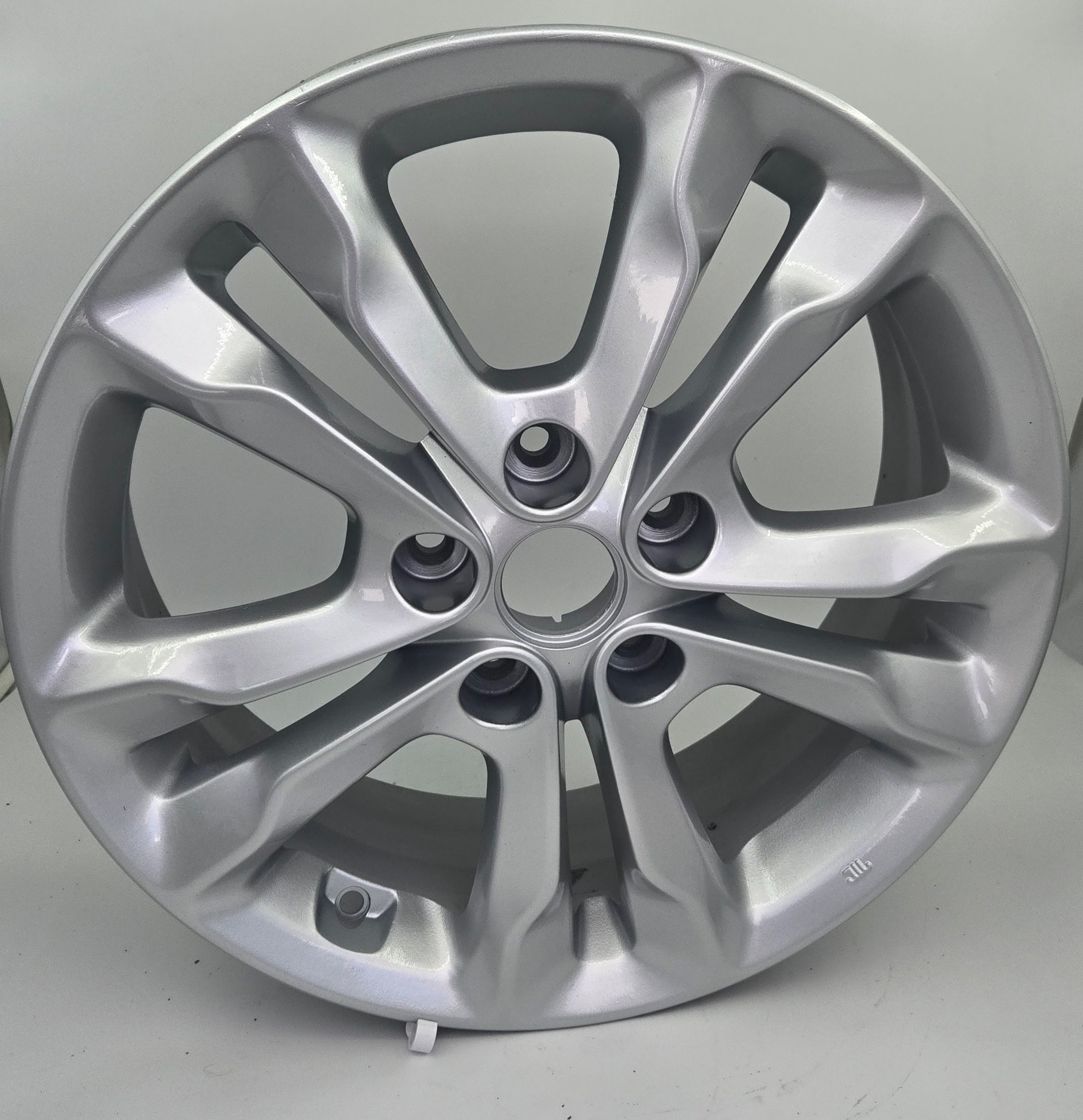 Close-up of a silver car wheel rim with a modern, multi-spoke design.