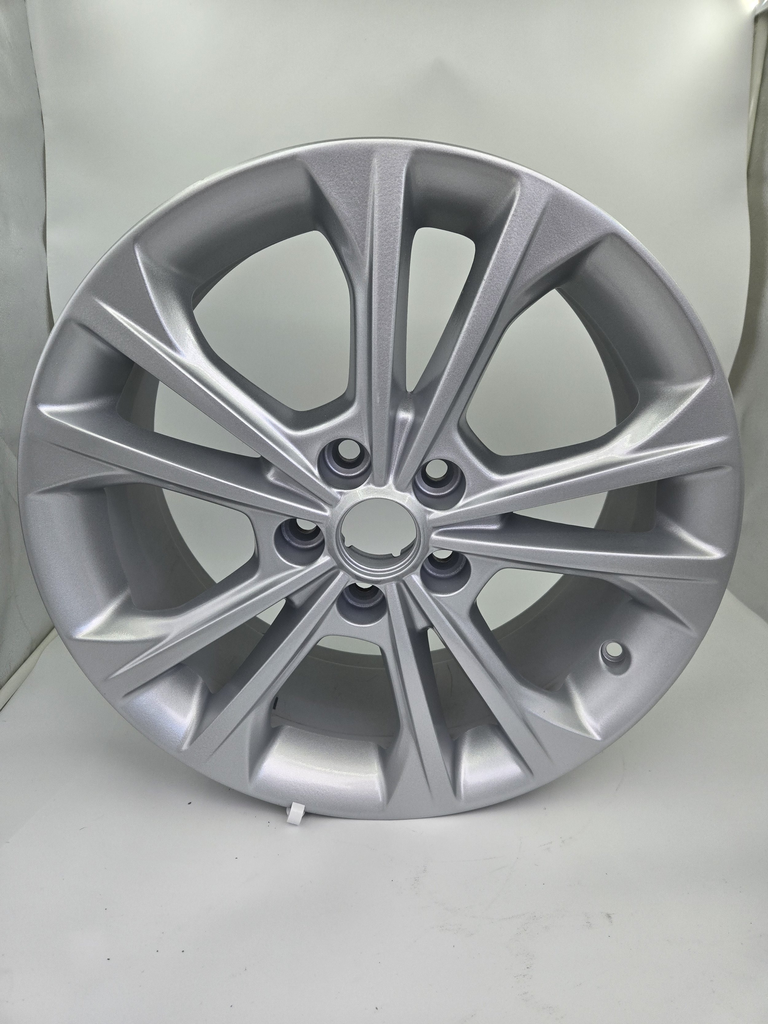 A silver alloy wheel rim for a vehicle on a white surface.