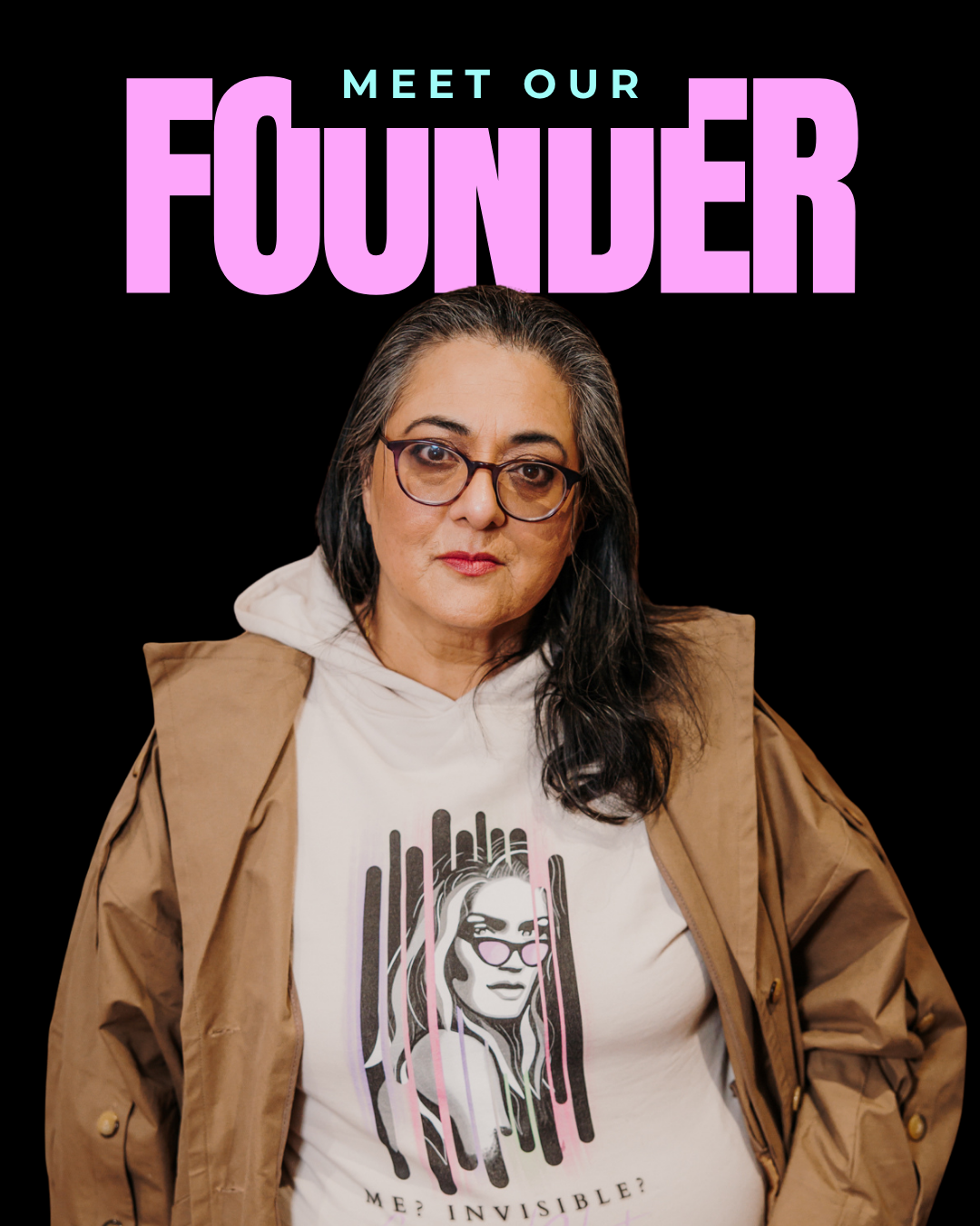 A woman with long dark hair, glasses, and wearing a beige jacket over a white hoodie and T-shirt with a stylized illustration of herself and the text "Me? Invisible?" on it. She is standing in front of a black background with the text "Meet Our Founder" in purple and teal above her head.
