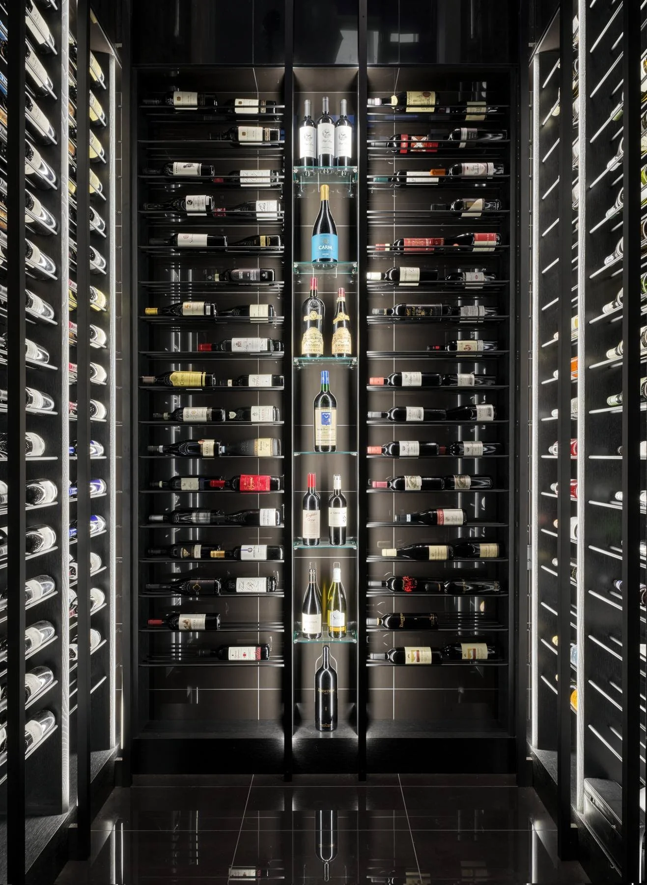 Floor-to-ceiling lit wine wall in black glass and steel