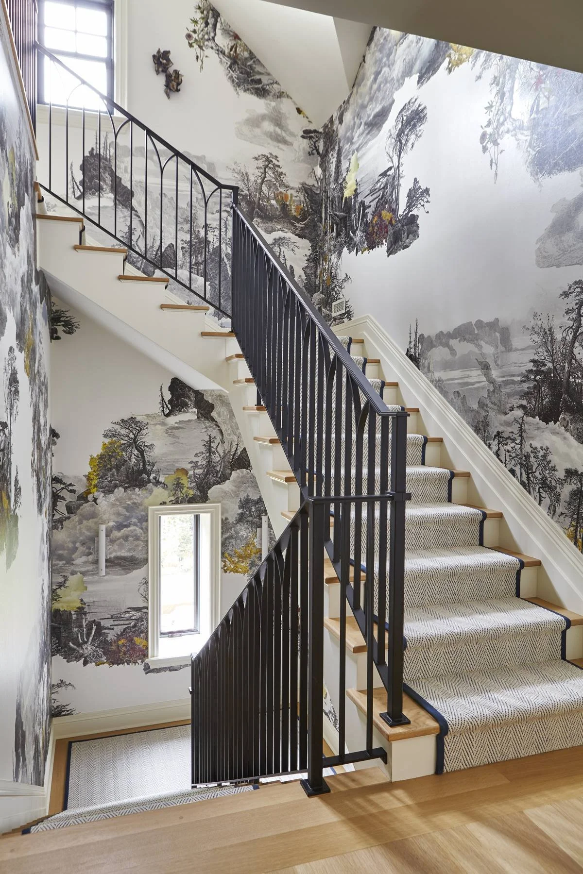 Curved staircase with iron railing and scenic wallpaper