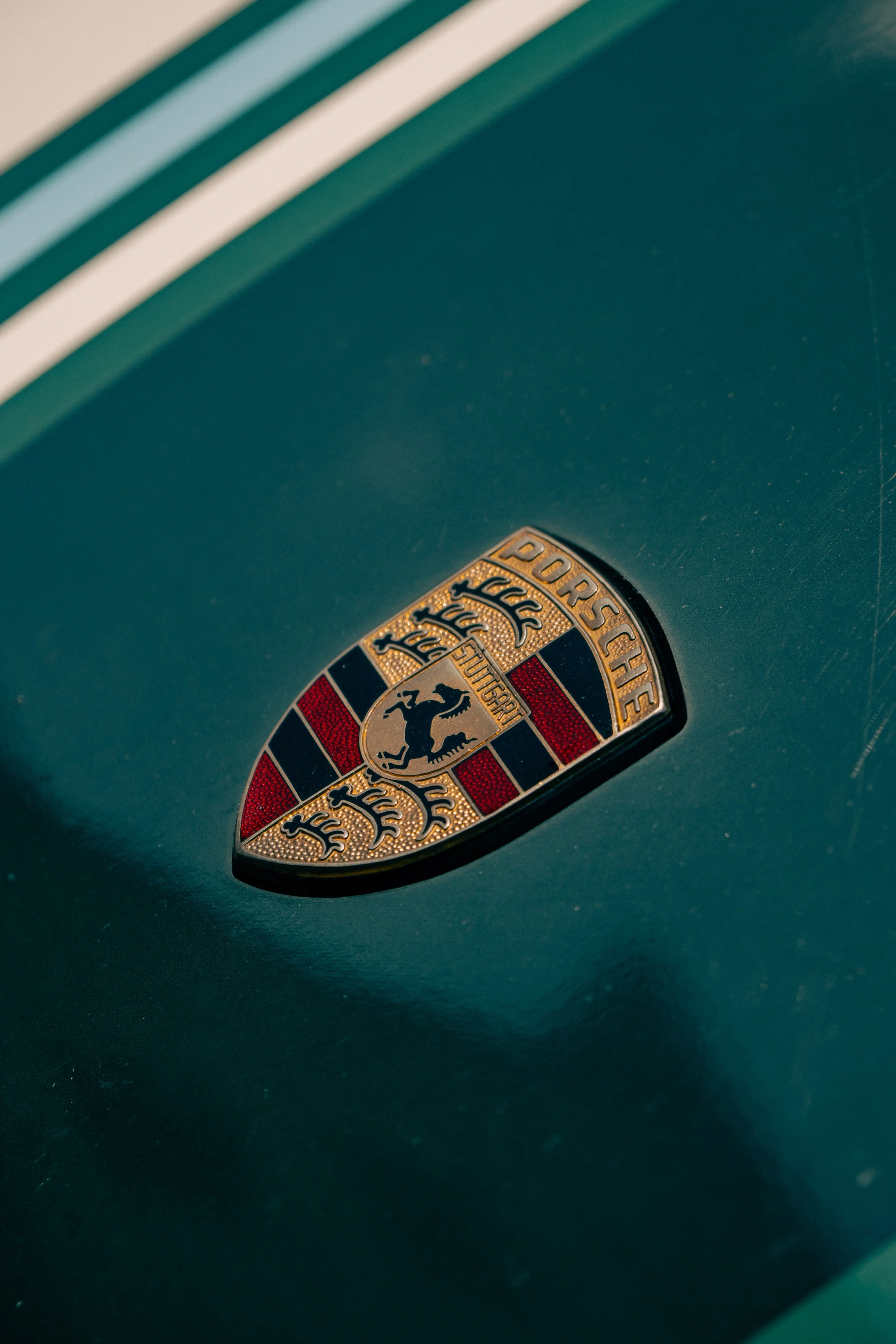Close-up of a green Porsche steering wheel with the Porsche crest badge in the center.