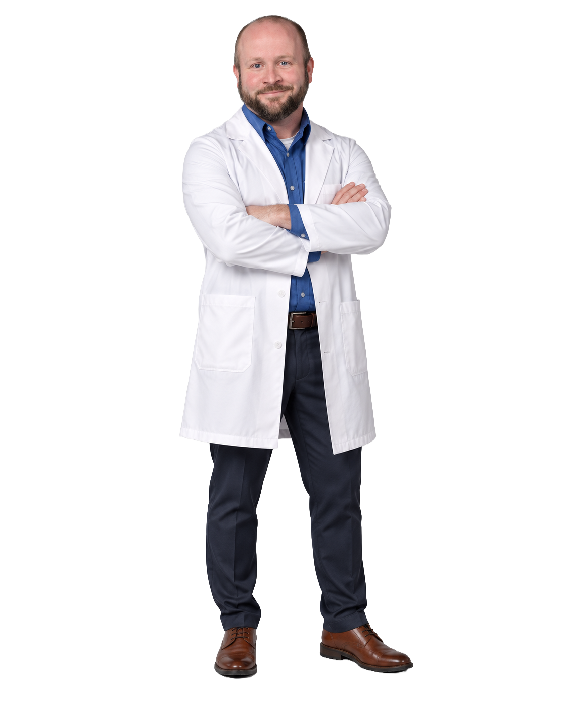 A male doctor standing with arms crossed, wearing a white lab coat over a blue dress shirt, dark trousers, brown shoes, and smiling.