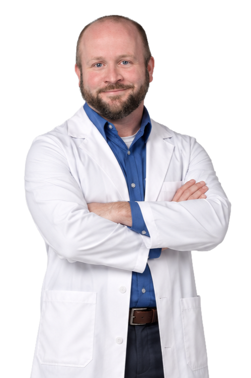Man in a white doctor's coat with arms crossed, smiling, wearing a blue collared shirt underneath.