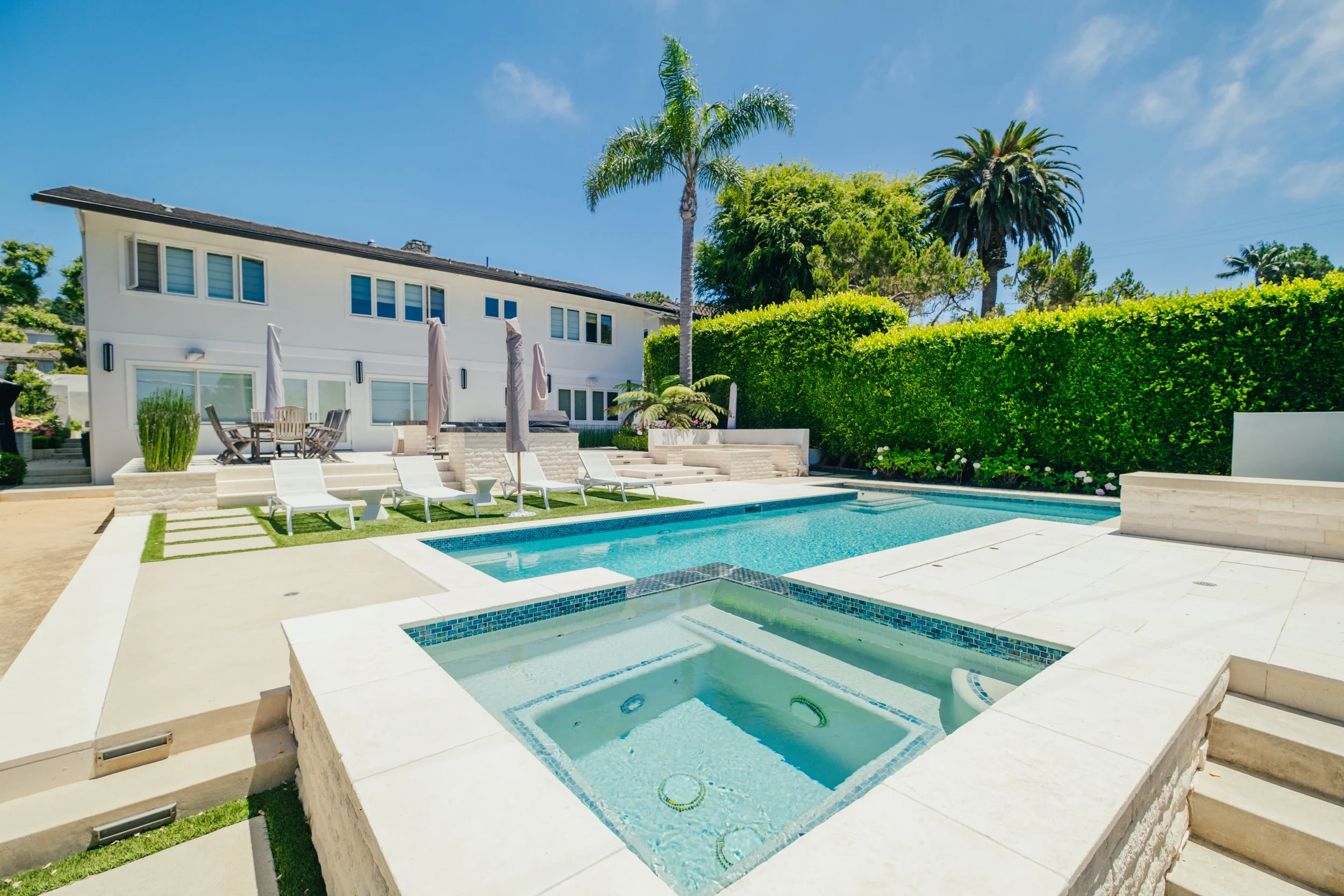 Custom outdoor kitchen and dining area beside a backyard pool by Rosewood Landscape in Rancho Palos Verdes, California