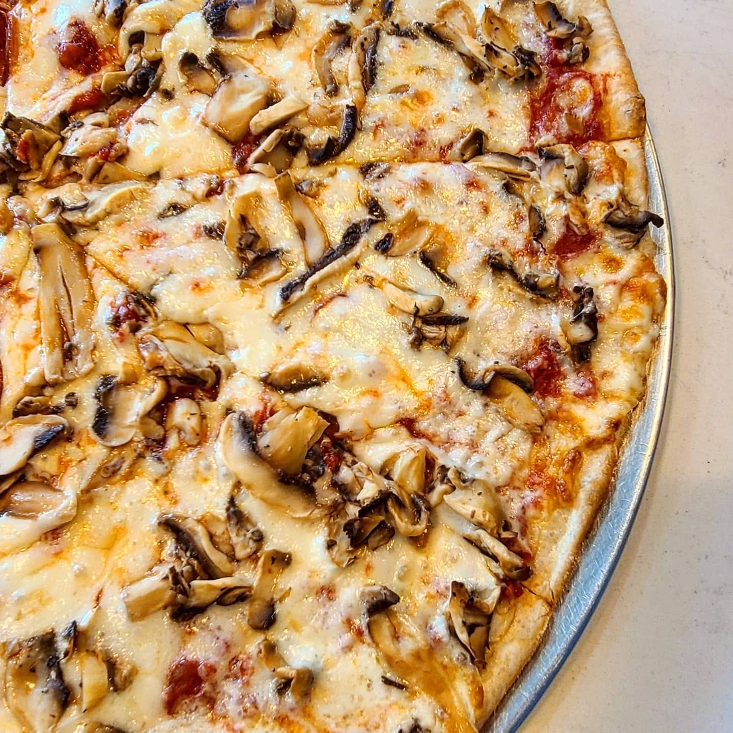 A close-up of a rectangular pizza topped with sliced mushrooms and melted cheese.