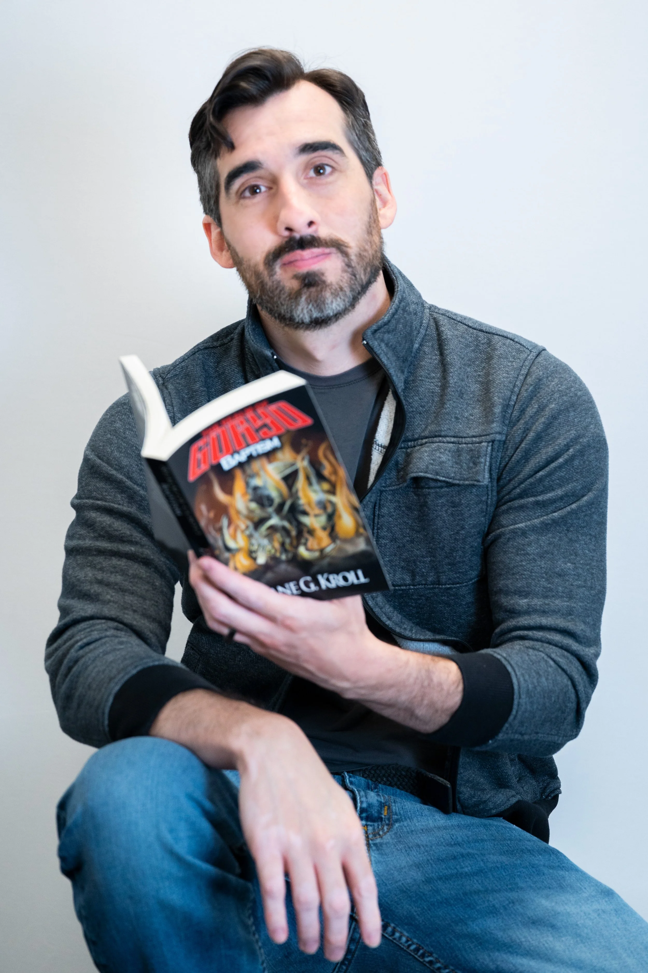 Author Dane G. Kroll sitting and holding an open illustrated book